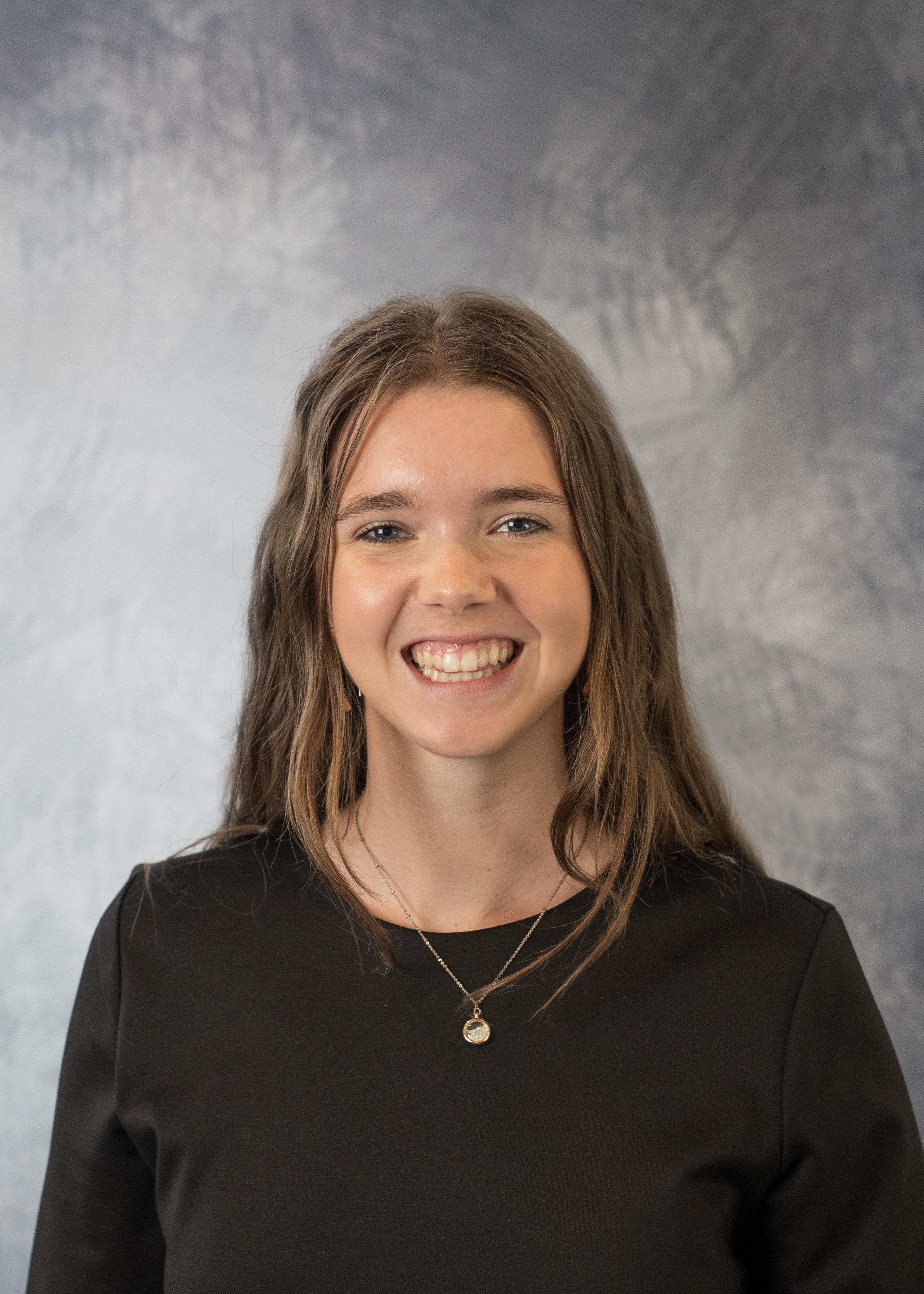 A headshot of Cora Garling against a grey background